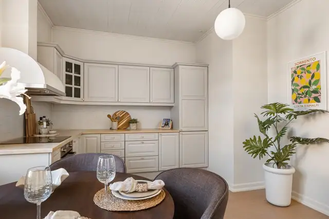 Fliser over benkeplaten gir et stilrent og praktisk uttrykk. Rommet har en hyggelig spiseplass ved vinduet, som slipper inn rikelig med naturlig lys og gir en luftig atmosfære.