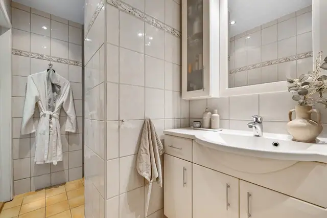 Badet er praktisk innredet og har flislagte gulv og vegger som gir et helhetlig og slitesterkt uttrykk.