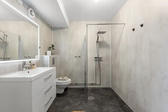 Badet har belegg på gulv, våtromsplater på vegger og malt overflate i himlingen.