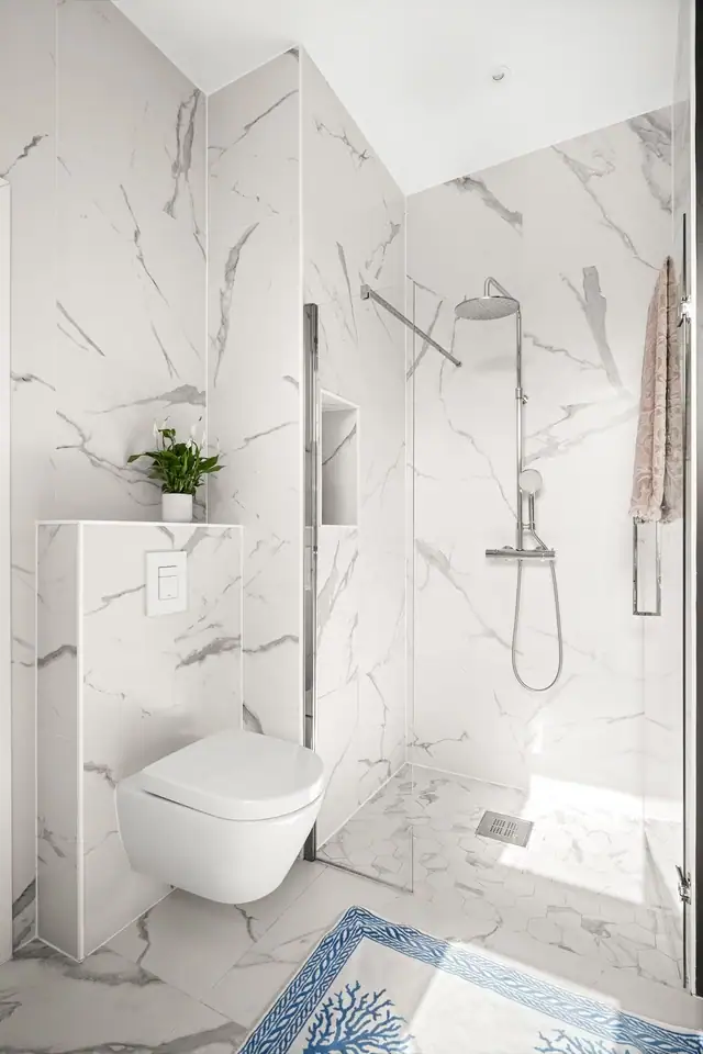 Badet har store, smakfulle fliser på vegger og gulv, med unntak av én kontrastvegg, og er utstyrt med downlights i himling samt behagelig gulvvarme.