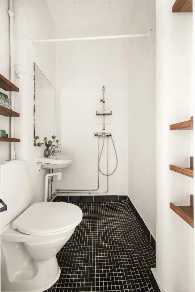 Badet har overflater med fliser på gulvet, strié på veggene med varmelampe og malt himling. Badet er utstyrt med toalett, vegghengt servant og dusjhjørne.