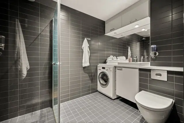 Stort bad fra byggeår med flislagte overflater, downlights og gulvvarme. Badet er utstyrt med dusjhjørne med innfellbare glassdører, vegghengt toalett og baderomsmøbel med skap, innfelt servant med ettgreps blandebatteri, speil og belysning.
