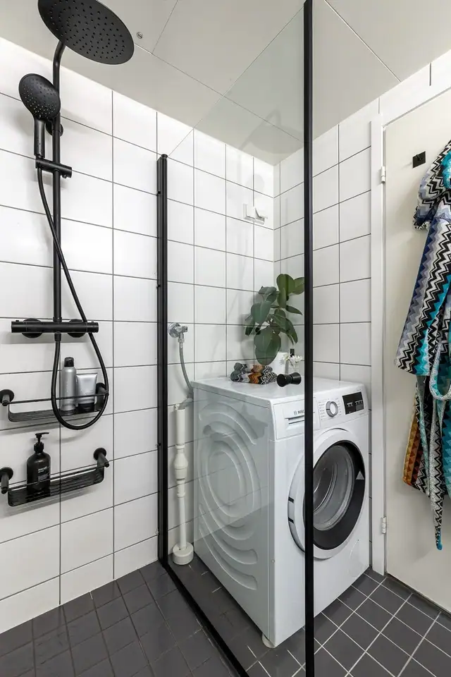 Badet er innredet med veggmontert toalett, dusjplass med inn- og utadslående dusjvegger og baderomsmøbel med skuffer og servant med ettgreps blandebatteri.