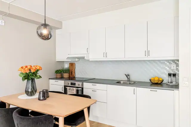 Pent kjøkken med lyse fronter og benkeplate av laminat.