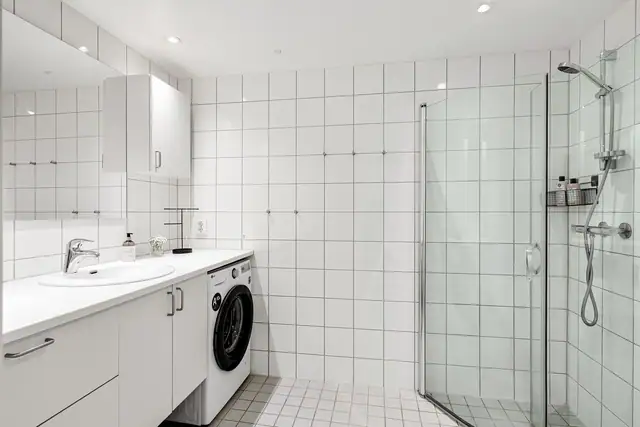 Lyst baderom med flislagte overflater, behagelig gulvvarme og downlights i himlingen.