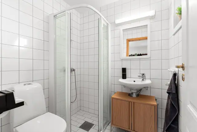 Praktisk og flislagt bad med gulvvarme. Badet er utstyrt med mekanisk avtrekk, dusjhjørne, WC og servant med ettgreps blandebatteri.