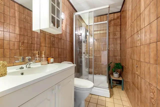 Badet er utstyrt med gulvmontert toalett, baderomsinnredning med heldekkende servant og ettgreps blandebatteri, samt dusjkabinett.