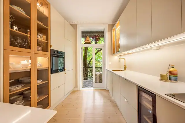 Tidsriktig innredning med beige, glatte fronter samt benkeplate og backsplash i komposittstein. Det er Tapwell vask og armatur.
